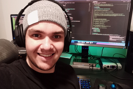 CIS student smiling and wearing headphones in front of a coding terminal