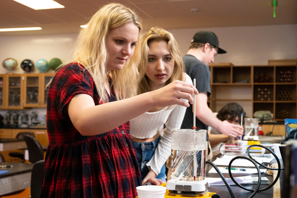 Engineering and physics students measuring fluid in a large beaker