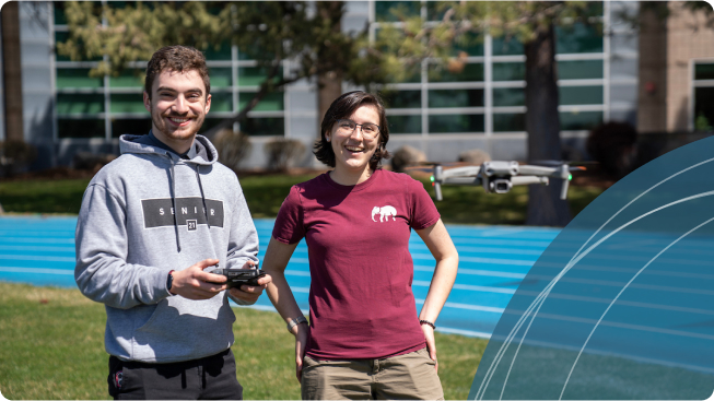 Two smiling Central Oregon Community College students learning to piloting a drone together.