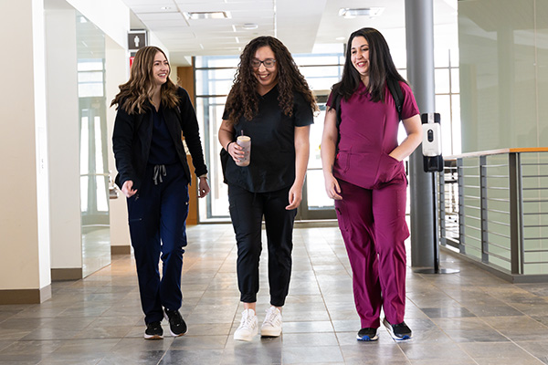 Three medical students walking together down a hallway
