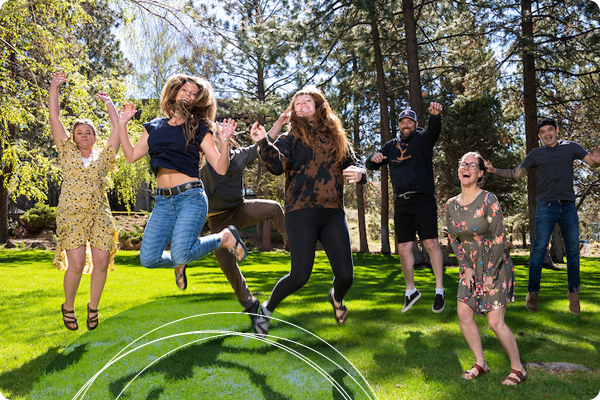 Community college students jumping together on grassy lawn