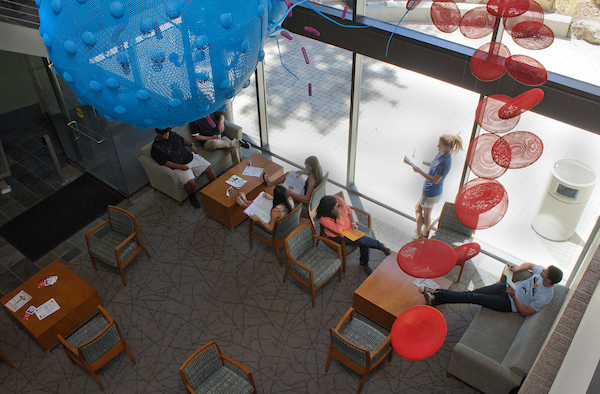 Students sitting in the lounge area of the Health Careers Center, underneath a sculpture of a red blood cell 