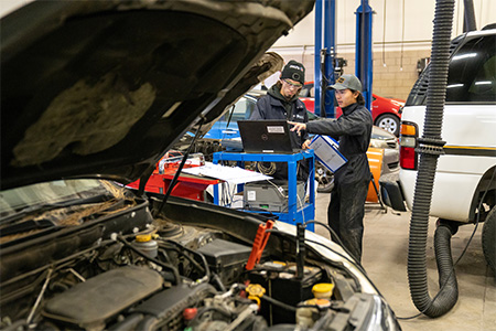 Two COCC Automotive students working on a car together.