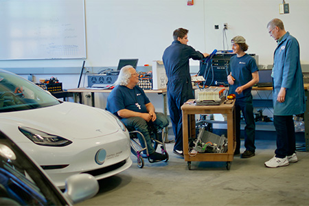 COCC Automotive Technology faculty member stands with 3 students in garage lab.