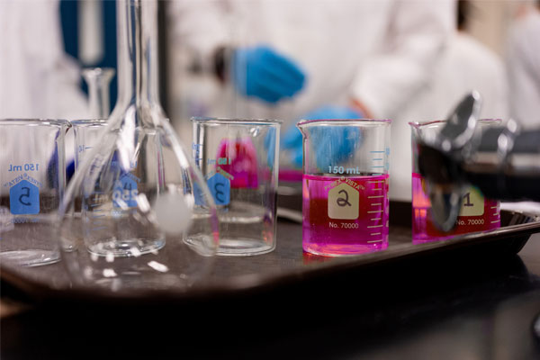 Chemistry lab glassware with fuschia liquid solutions during a hands-on experiment at COCC