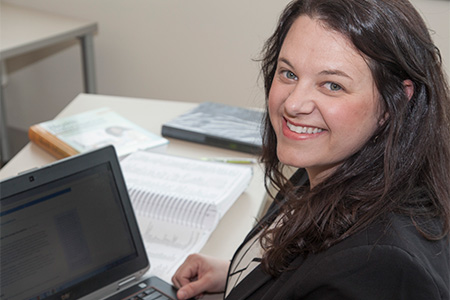 Woman working at a computer, smiling at the camera.