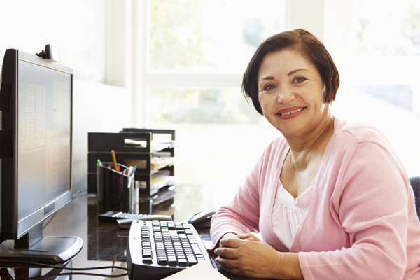 Health Information Management worker smiling in front of her computer terminal