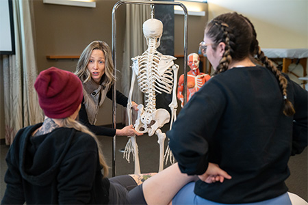 Woman using a skeleton to demonstrate to students.