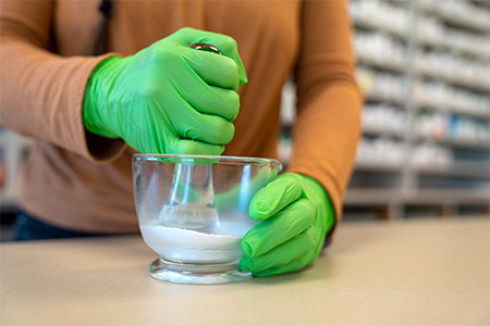 Hands of a pharm tech student practicing mixing in the lab.