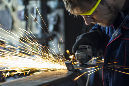 Apprentice grinding metal with sparks flying