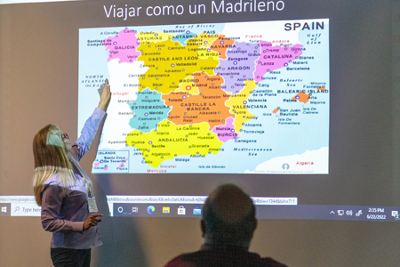 Community college world language instructor pointing at spain on a big map