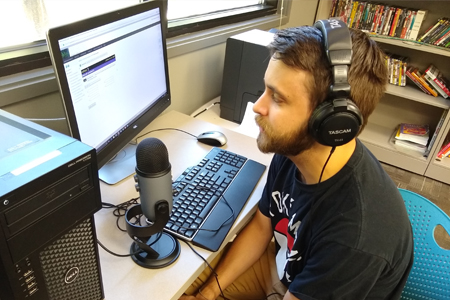 World languages student learning at computer with microphone
